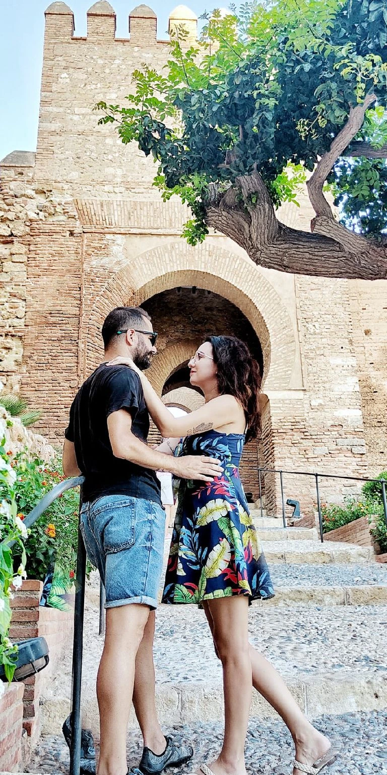 Raissa e Jesús apreciam a imponente Puerta de la Justicia do Alcazaba de Almería enquanto planejam sua jornada explorando os lugares para descobrir em Almería e mergulhando na riqueza cultural desta cidade.