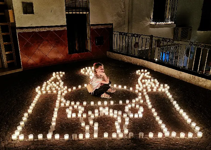 Menina sentada entre velas que formam o desenho de um palácio árabe no Festival Luna Mora de Guaro