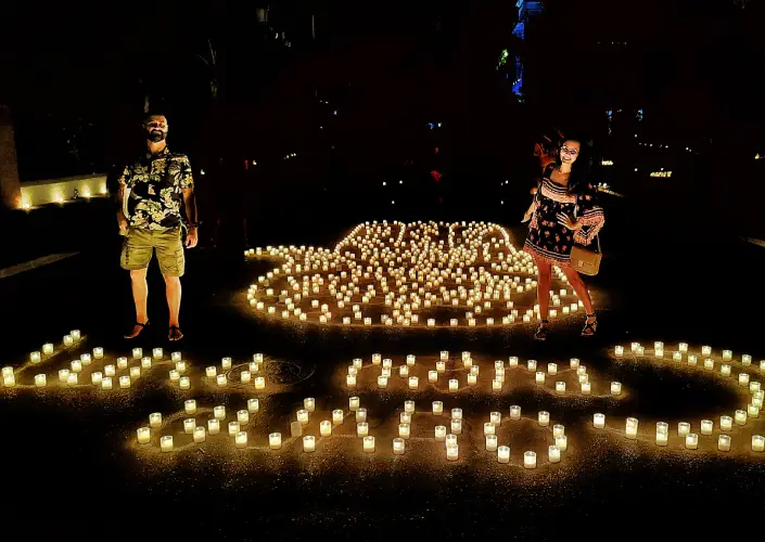 Casal em frente ao desenho de velas da Mão de Fátima no Festival Luna Mora de Guaro